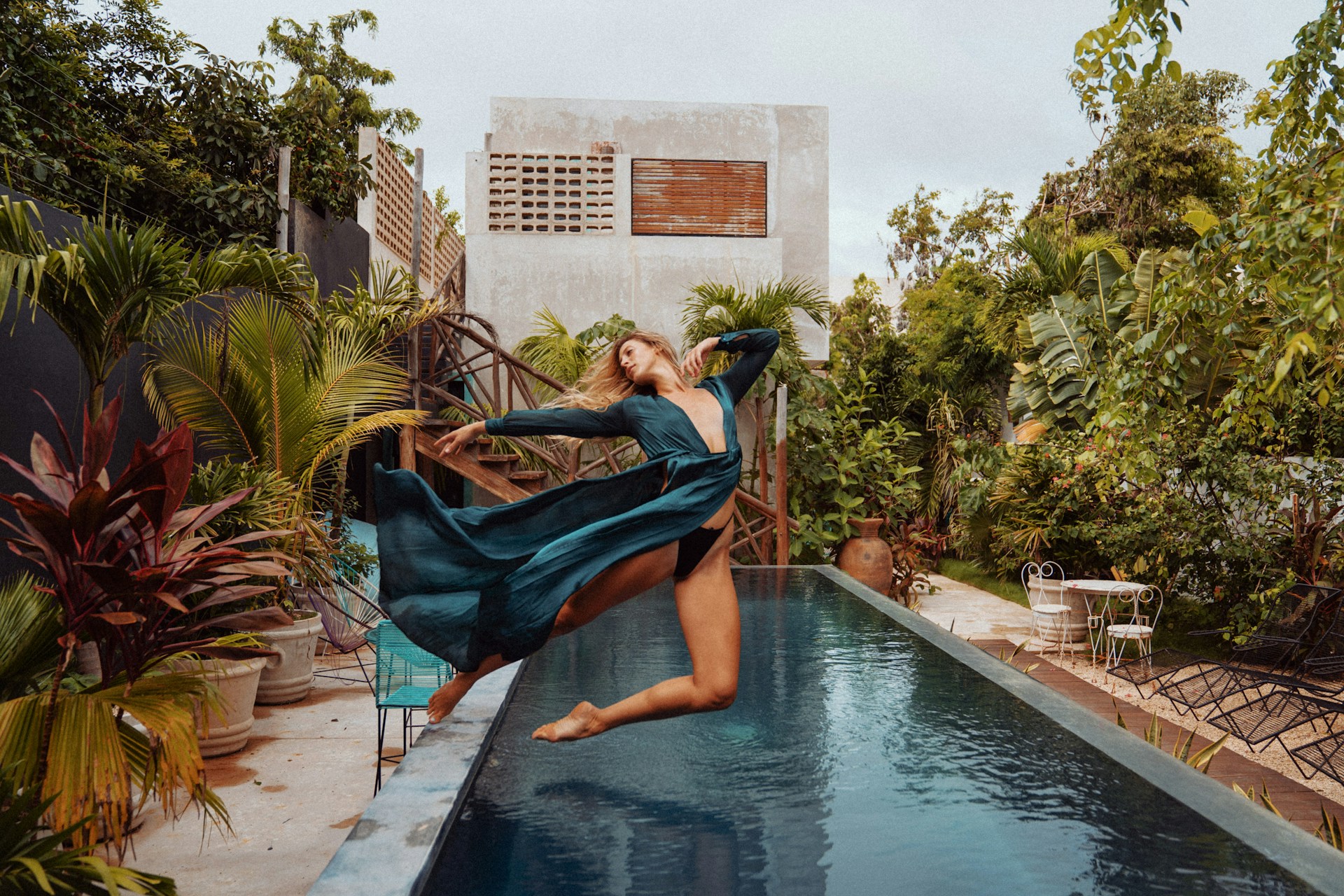 woman in blue dress sitting on swimming pool during daytime